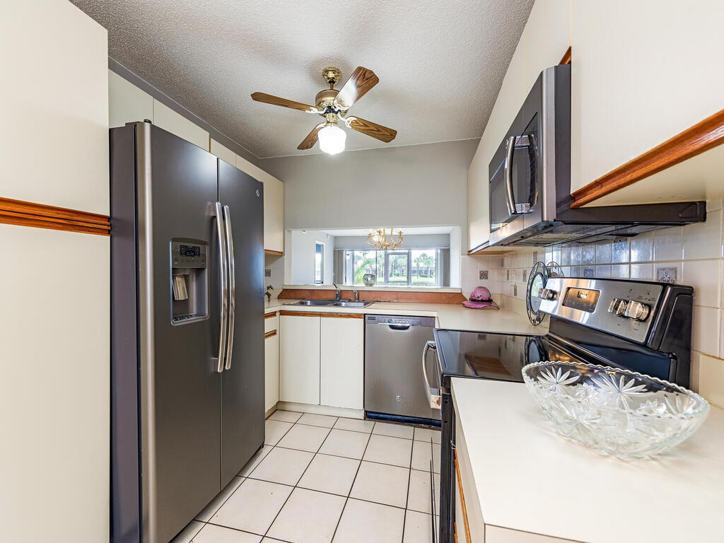 740 Augusta Boulevard, Unit E101 Naples, FL 34113 - Photo 5 of 12 a kitchen with stainless steel appliances granite countertop a sink a stove and a refrigerator