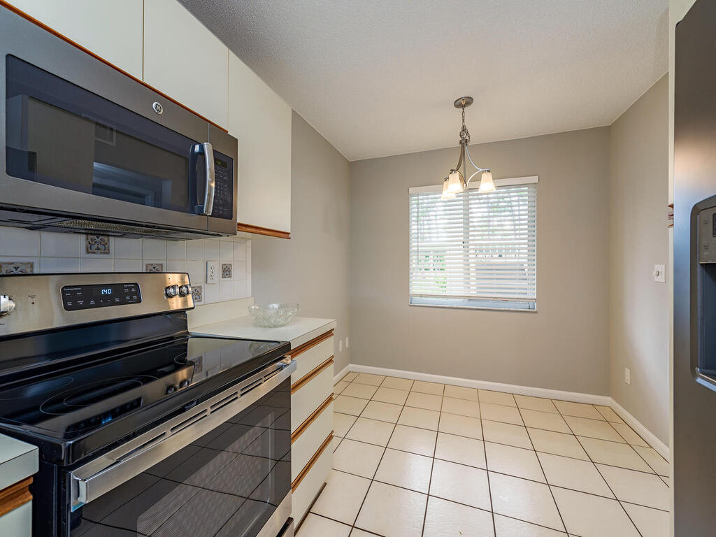 740 Augusta Boulevard, Unit E101 Naples, FL 34113 - Photo 6 of 12 a kitchen with a stove a microwave and cabinets