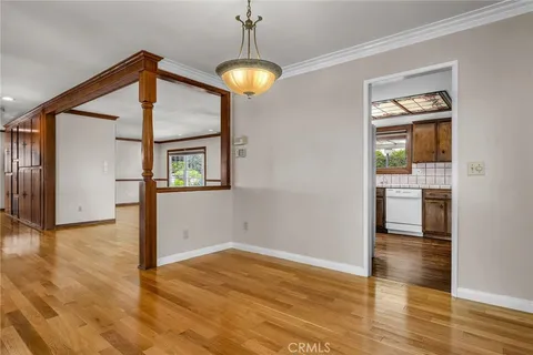 a view of a hallway with wooden floor and a kitchen