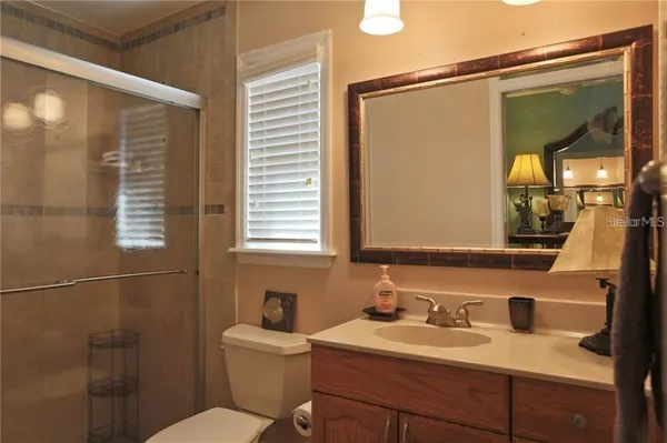 a bathroom with a granite countertop sink toilet a mirror and shower