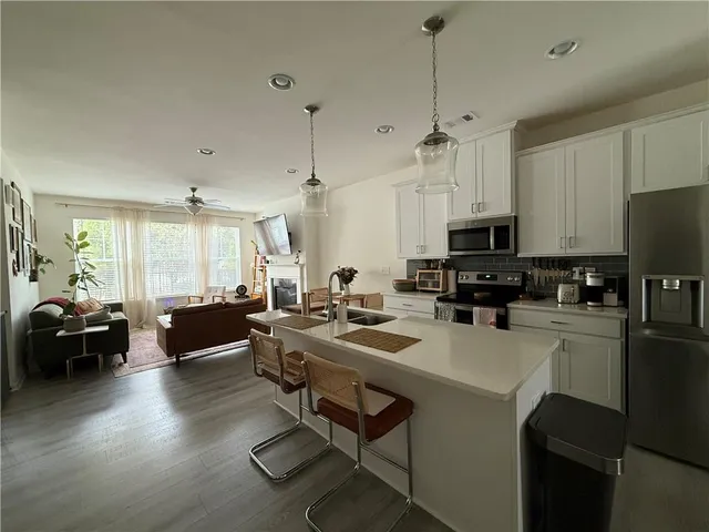 a kitchen with a stove a refrigerator and a living room view