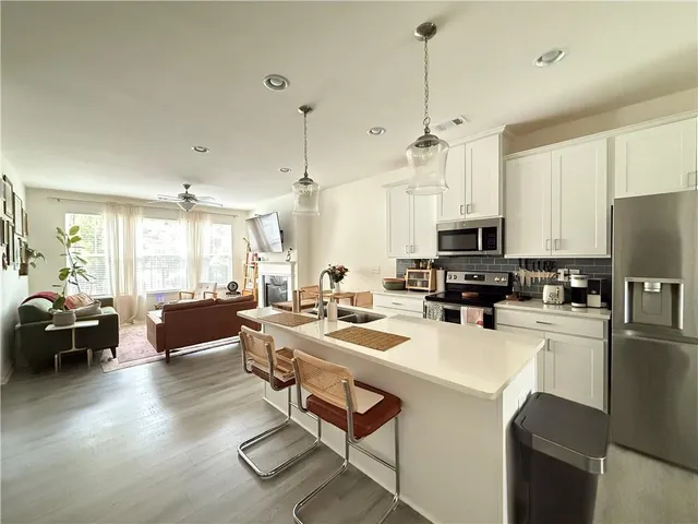 a kitchen with stainless steel appliances a refrigerator a stove a sink dishwasher a oven with white cabinets and wooden floor