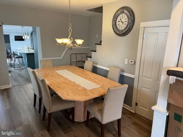 a dining room with a table chairs a clock and a large mirror