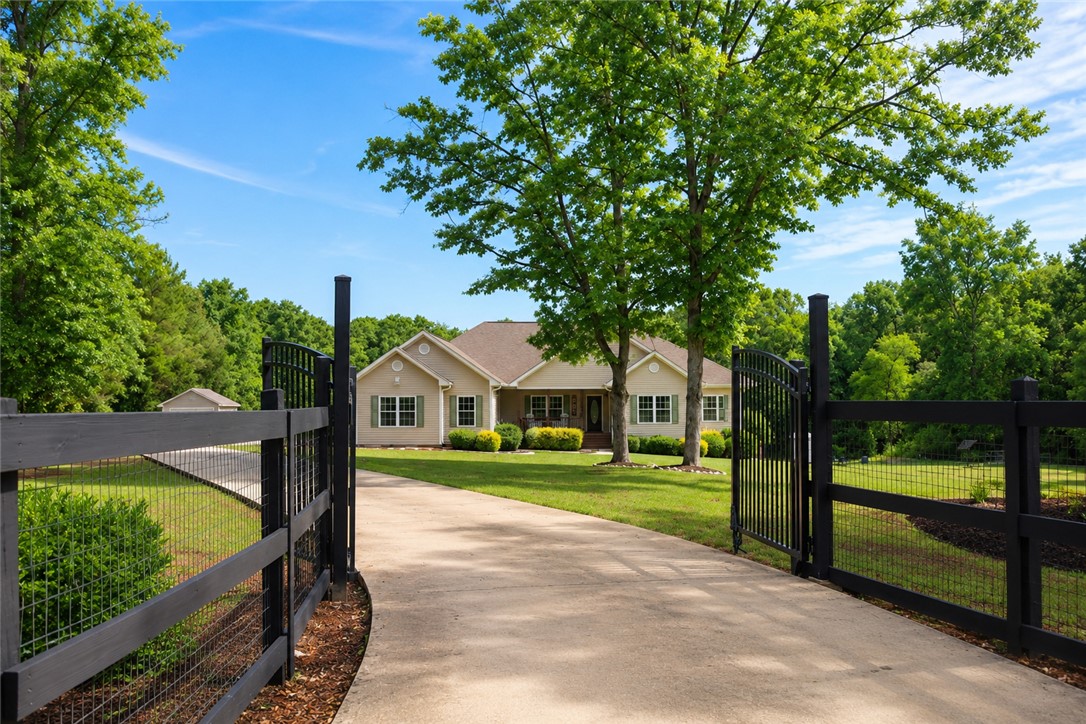 190 Fred Bradford Road Iva, SC 29655 - Photo 1 of 32 A graceful home nestled amidst verdant trees, featuring a concrete driveway and elegant fencing.