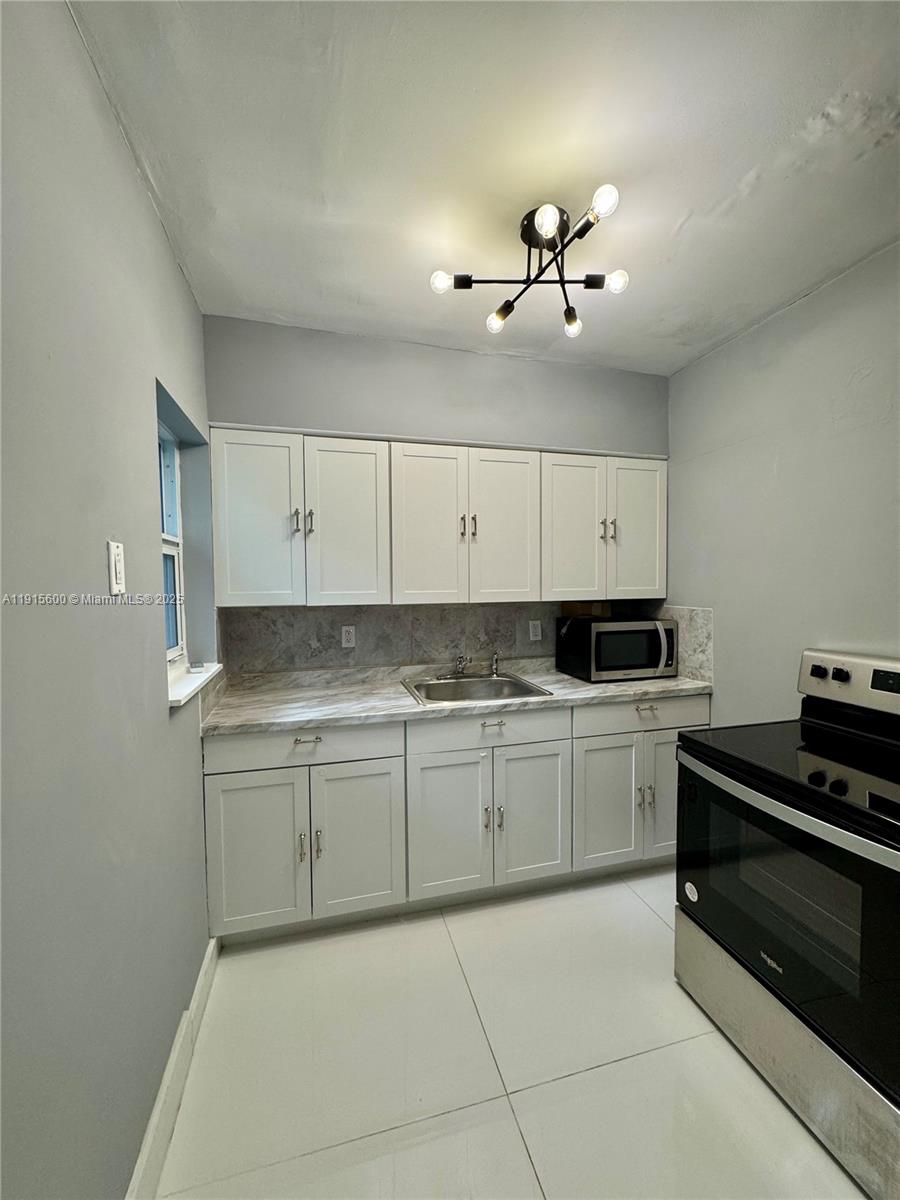 300 Mendoza Avenue, Unit 3 Coral Gables, FL 33134 - Photo 16 of 19 a kitchen with a stove cabinets and chandelier