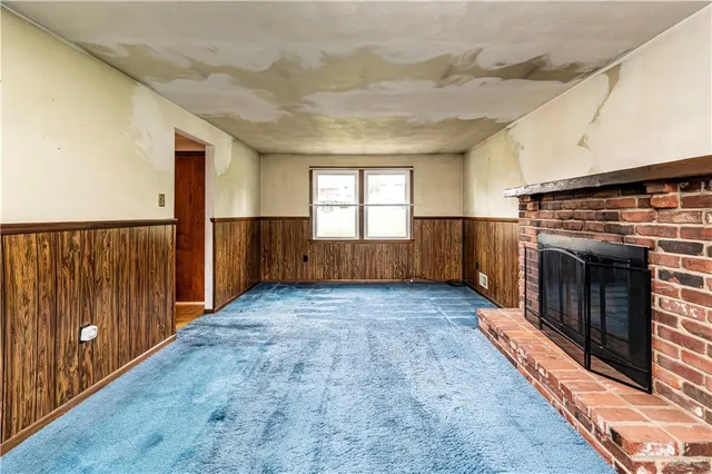 a view of an empty room with wooden floor fireplace and a window
