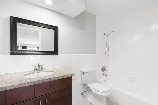 a bathroom with a granite countertop toilet sink and mirror
