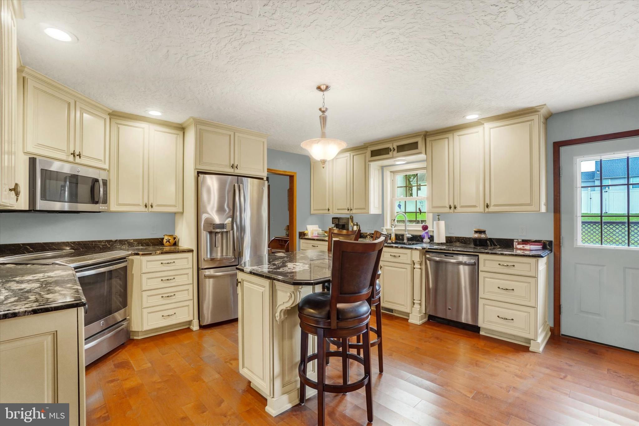 441 School Road York, PA 17407 - Photo 13 of 34 a kitchen with stainless steel appliances granite countertop a stove top oven a refrigerator a sink dishwasher a dining table and chairs with wooden floor