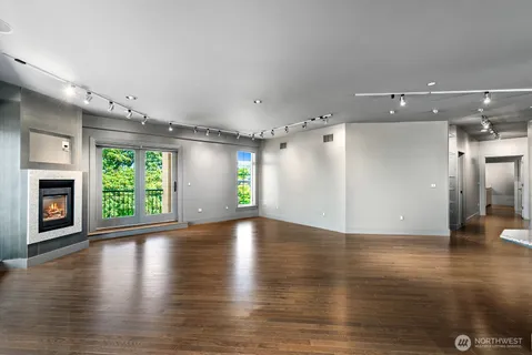 an empty room with wooden floor fireplace and windows