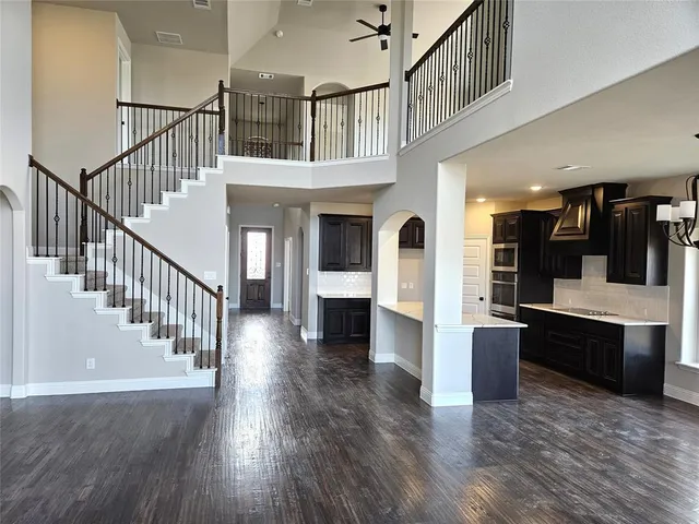 a view of staircase and kitchen with wooden floor and pendant lights