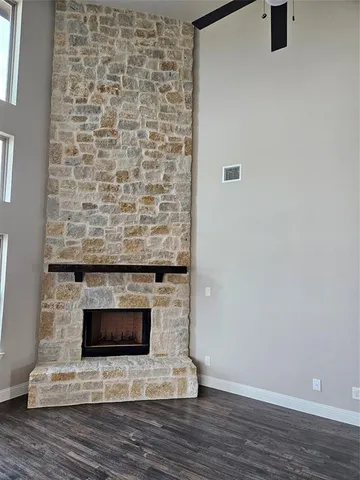 a view of an empty room with wooden floor and a fireplace