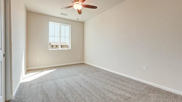 an empty room with a chandelier fan and windows