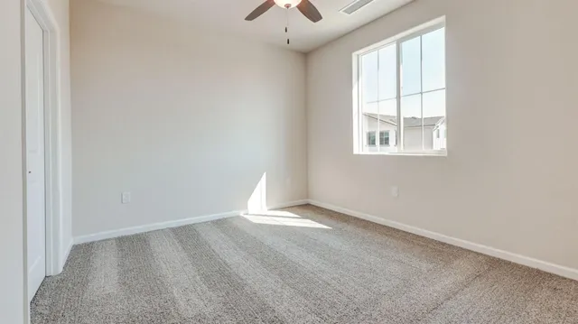 an empty room with windows and chandelier fan