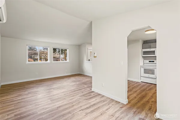 an empty room with wooden floor closet and windows