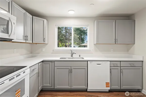 a kitchen with stainless steel appliances granite countertop a sink and cabinets with wooden floor