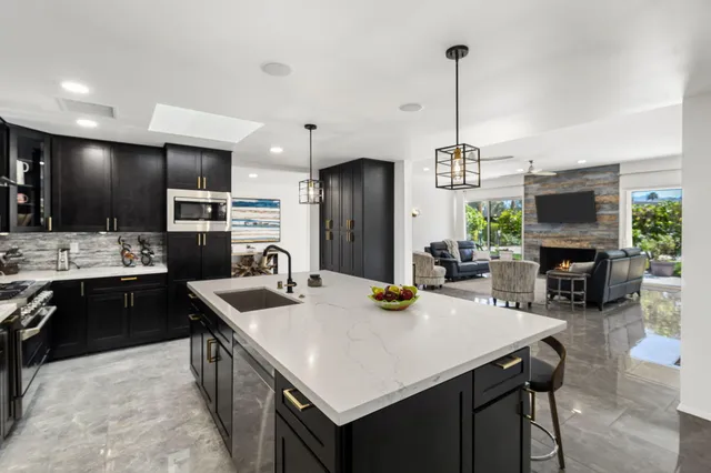 a kitchen with a refrigerator a sink dishwasher a stove and a dining table with wooden floor