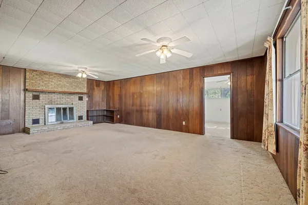 an empty room with chandelier fan and windows