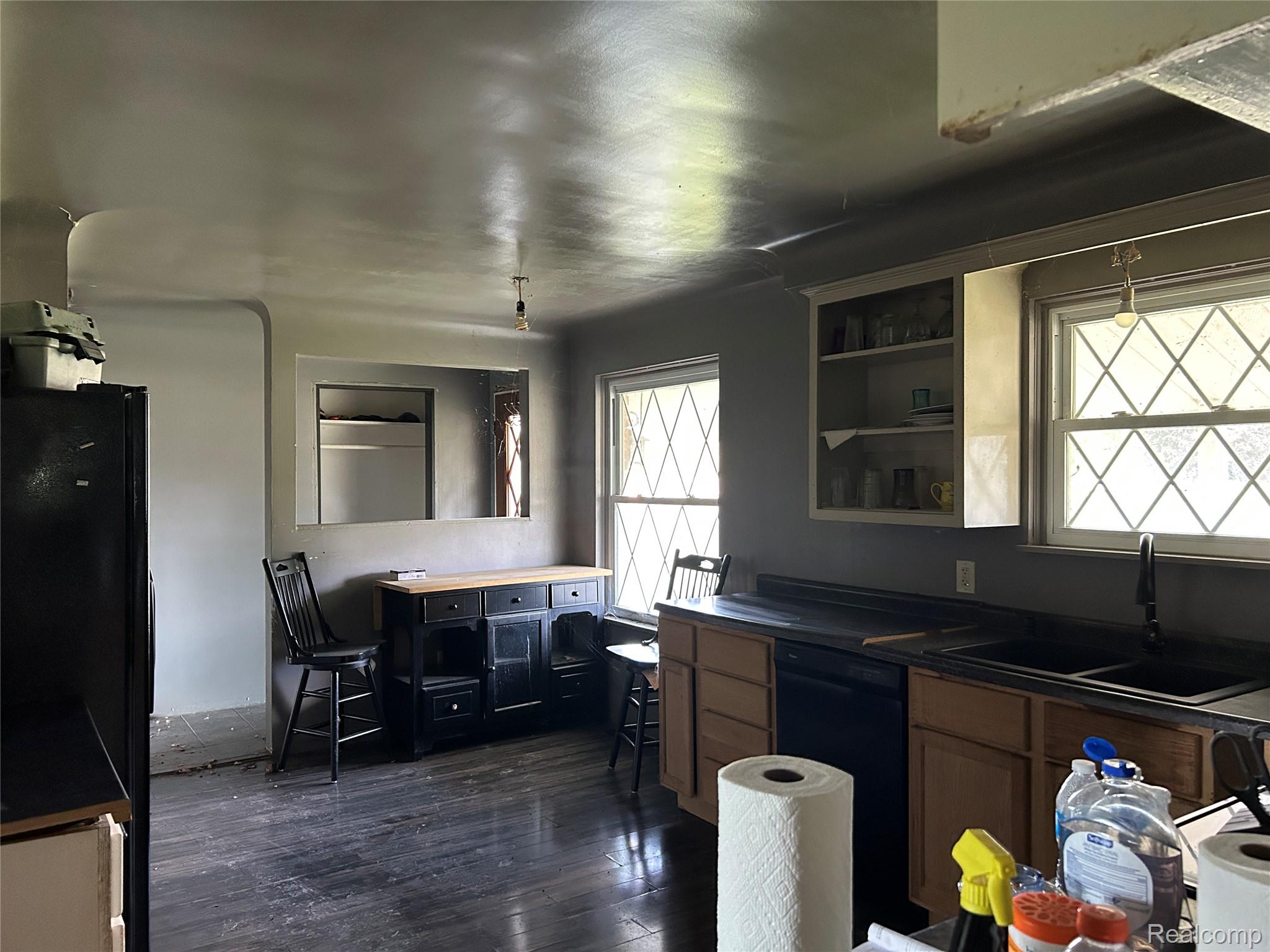 16465 Almont Road Allenton, MI 48002 - Photo 27 of 35 Kitchen featuring wood-finish flooring, two large windows with diamond-patterned grilles, built-in open shelving, and a dual-basin sink with a gooseneck faucet