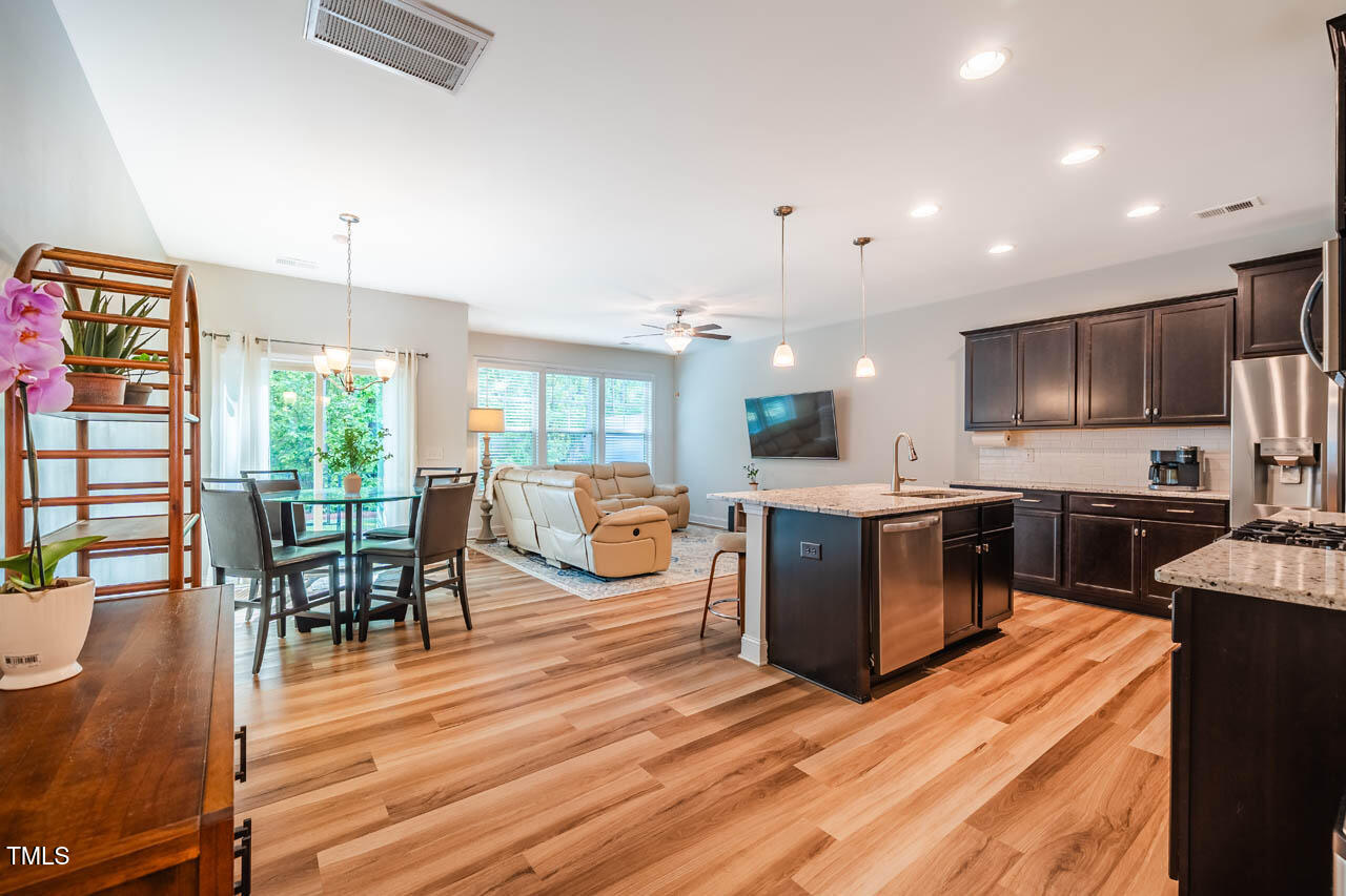 1101 Compass Drive Durham, NC 27713 - Photo 8 of 32 a kitchen with stainless steel appliances granite countertop a refrigerator a stove top oven a dining table and chairs with wooden floor