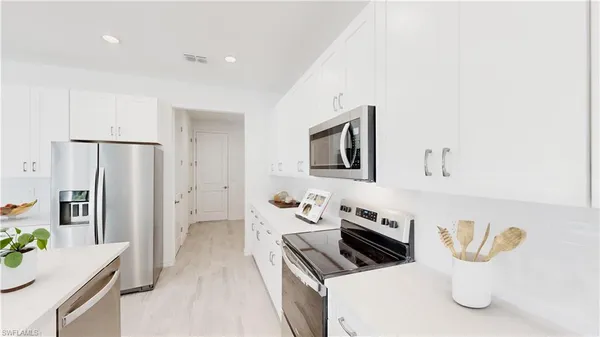 a kitchen with stainless steel appliances a microwave a refrigerator a stove a sink a dining table and chairs