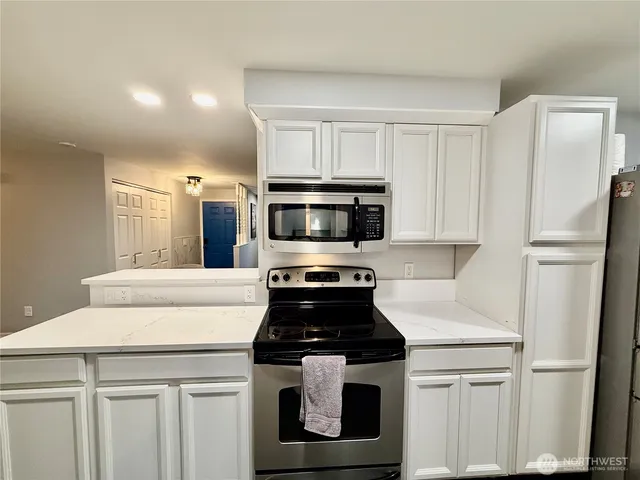 a kitchen with white cabinets and stainless steel appliances