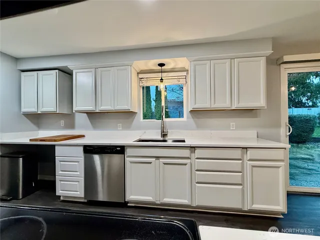 a kitchen with granite countertop white cabinets white appliances and a sink