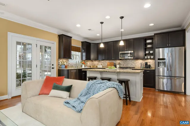 a kitchen with stainless steel appliances granite countertop a refrigerator a stove top oven a sink dishwasher and white cabinets with wooden floor