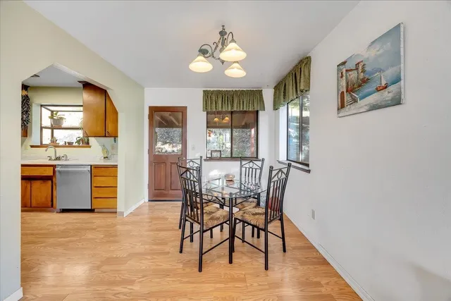 a kitchen with stainless steel appliances kitchen island granite countertop a refrigerator a stove a microwave oven with a dining table and chairs with wooden floor