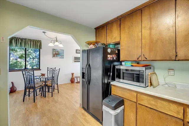 a kitchen with stainless steel appliances granite countertop a refrigerator a stove and a dining table with wooden floor