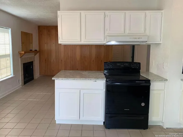 a kitchen with granite countertop white cabinets and appliances