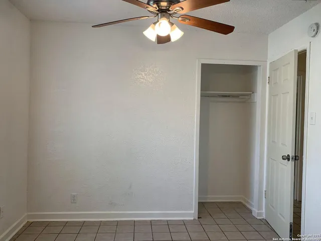 a view of an empty room with a ceiling fan and a window