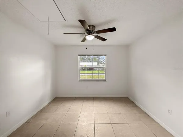 an empty room with a window and a ceiling fan