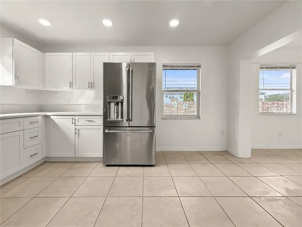 a kitchen with white cabinets a sink a stove a refrigerator and a window