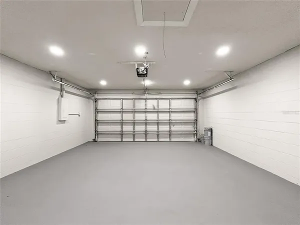 an empty room with white walls and chandelier fan