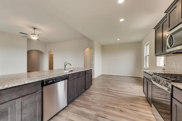 a kitchen with stainless steel appliances granite countertop a sink a stove and a wooden floors