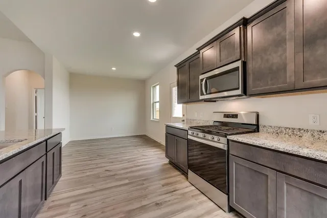 a kitchen with stainless steel appliances granite countertop a stove a sink and a microwave