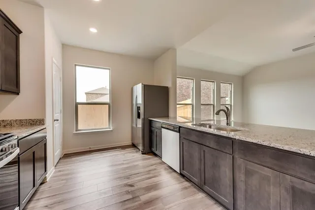 a kitchen with stainless steel appliances granite countertop a stove a sink and a refrigerator