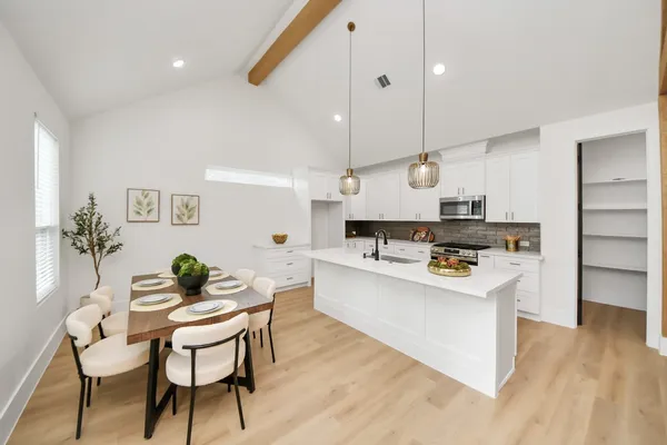 a kitchen with white cabinets and wooden floor