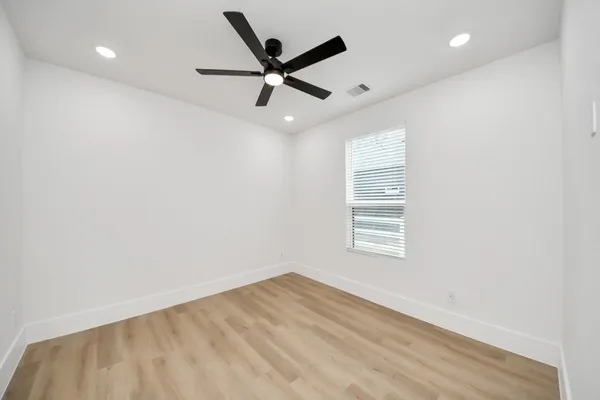an empty room with a window and a ceiling fan