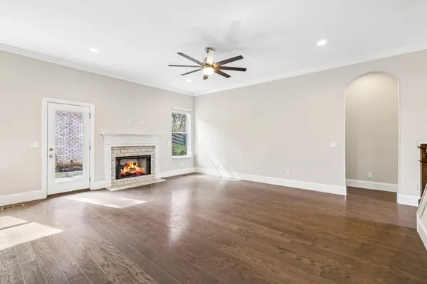 an empty room with windows fireplace and a fan