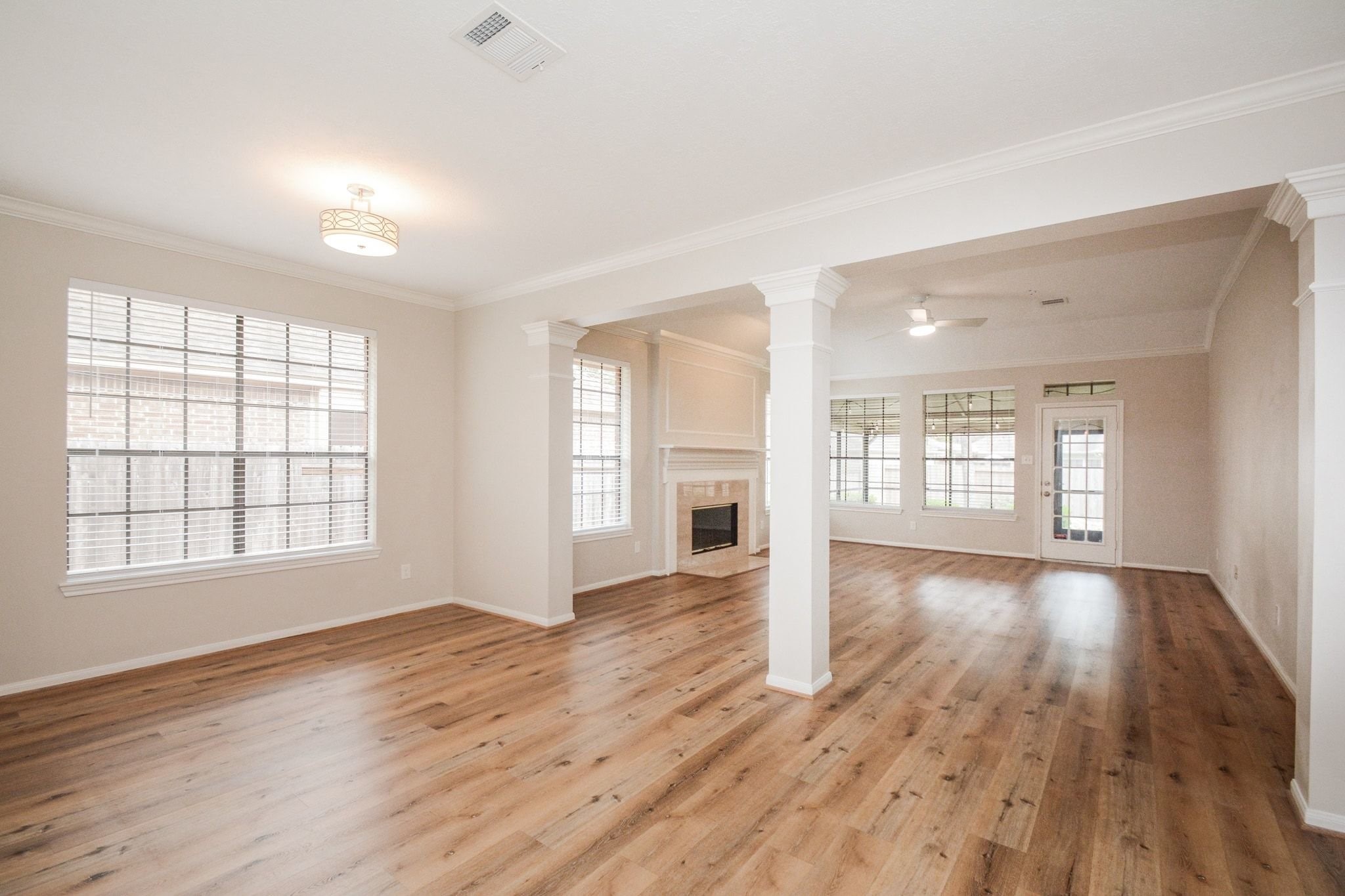 10 Heathstone Place The Woodlands, TX 77381 - Photo 22 of 27 Experience the charm of this spacious living area, featuring elegant hardwood flooring, abundant natural light from large windows, a cozy fireplace, and a ceiling fan, all within an open layout that complements any decor style.