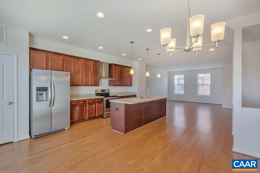 2172 Avinity Loop Charlottesville, VA 22902 - Photo 8 of 19 a kitchen with stainless steel appliances kitchen island granite countertop a refrigerator a sink dishwasher a stove and a dining table with wooden floor