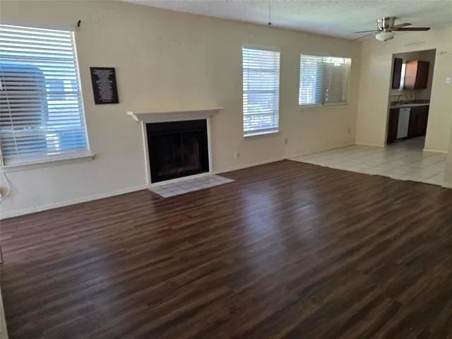 a view of an empty room with wooden floor fireplace and a window