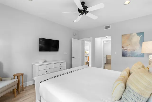 a bedroom with a bed a tv and wooden floor