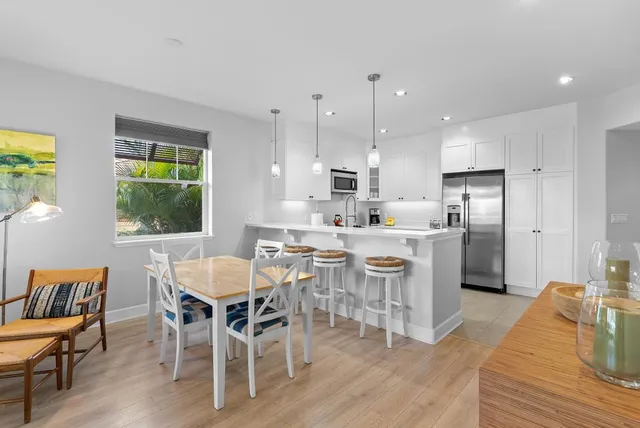 a dining room with stainless steel appliances kitchen island granite countertop a dining table chairs and window