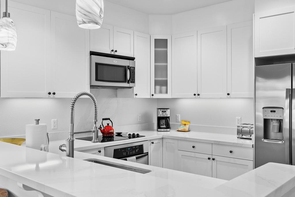 69-1033 Nawahine Place, Unit 22H Waikoloa, HI 96738 - Photo 4 of 29 a kitchen with white cabinets and stainless steel appliances