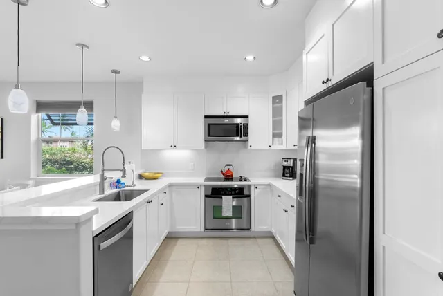 a kitchen with stainless steel appliances granite countertop a refrigerator a sink a stove and a wooden floors