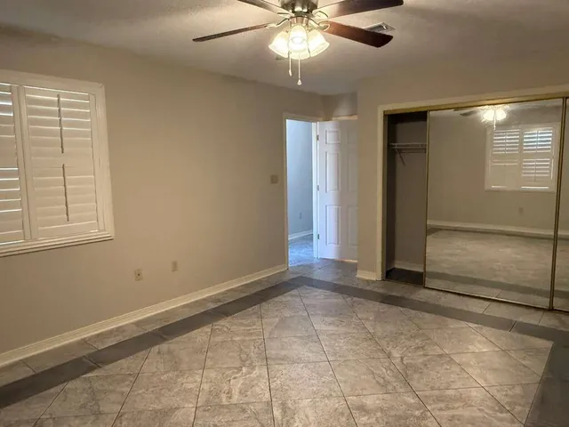 a view of an empty room with window and chandelier fan
