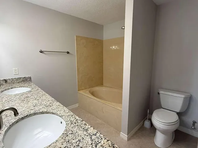 a bathroom with a granite countertop sink a toilet and bathtub