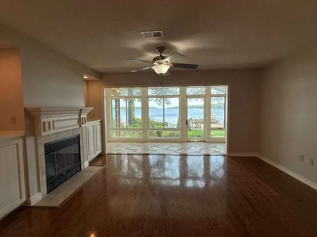 an empty room with fireplace wooden floor and windows